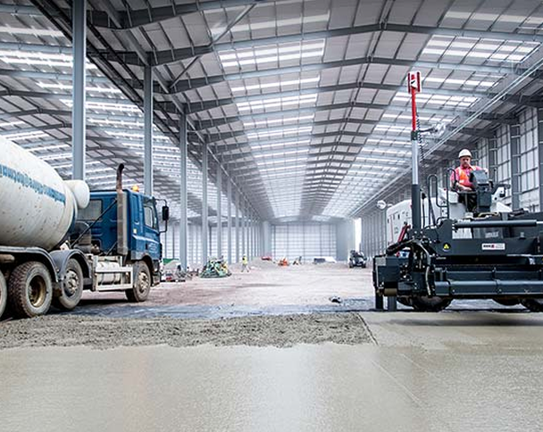 Warehouse interior with worker leveling concrete.